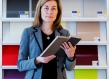Natalia Pokinska holding notebooks in front of paper shelf